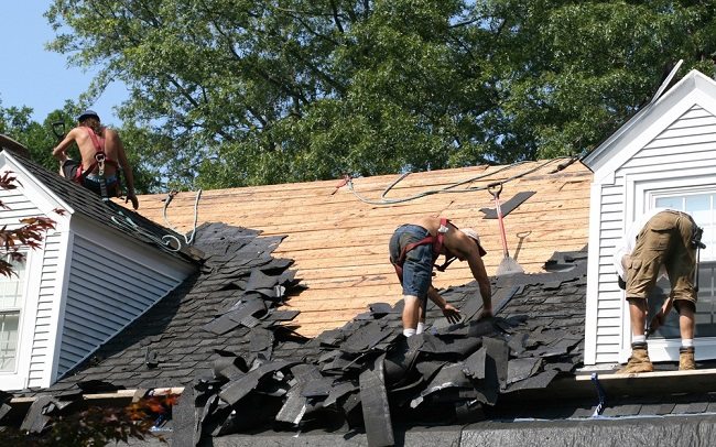 3 roofing workers stripping away old roofing materials