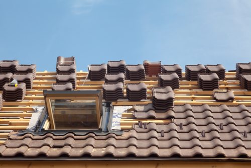 Stacks of brown roof tiles on roof in process of construction